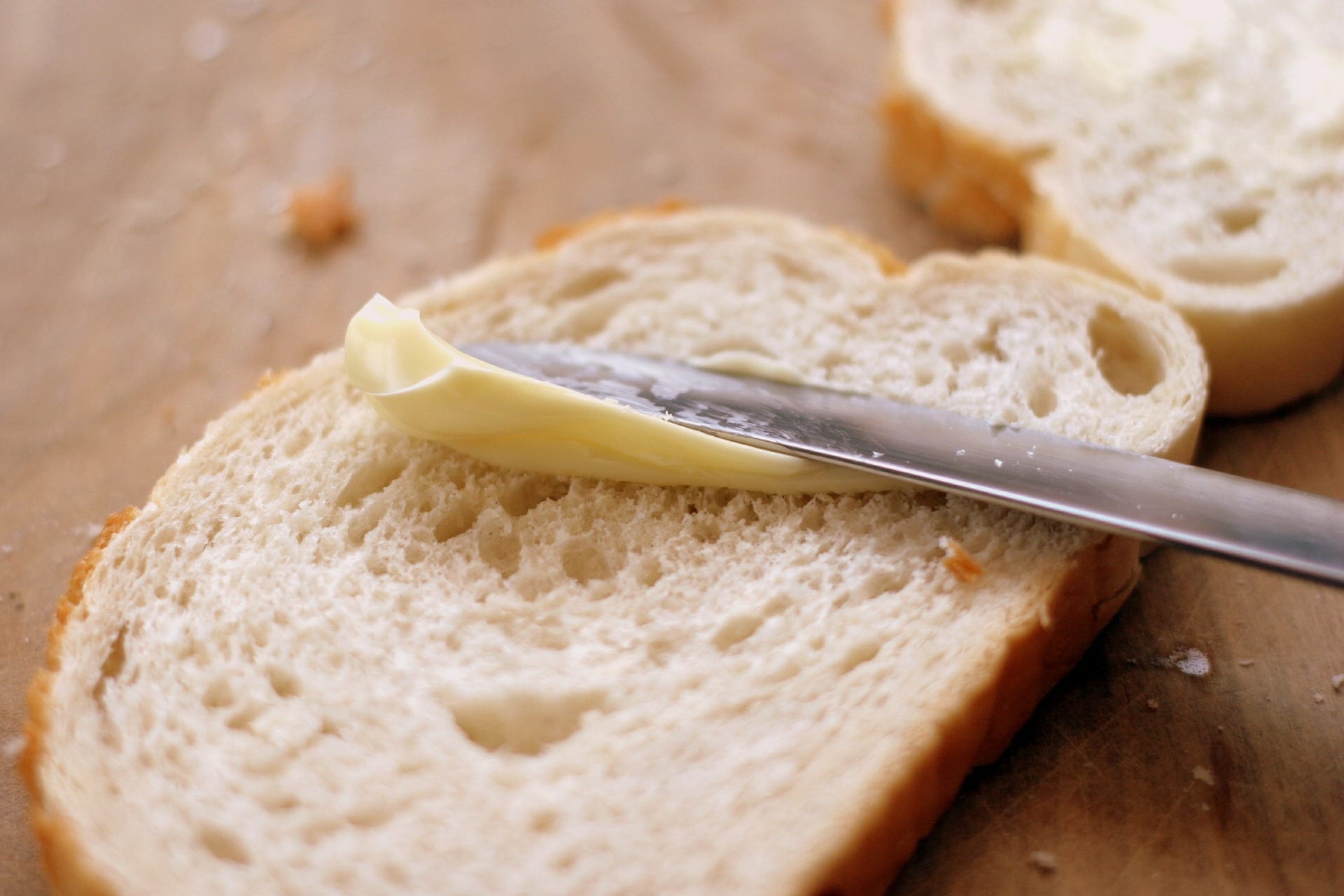 Bread with margarine being spread on it.