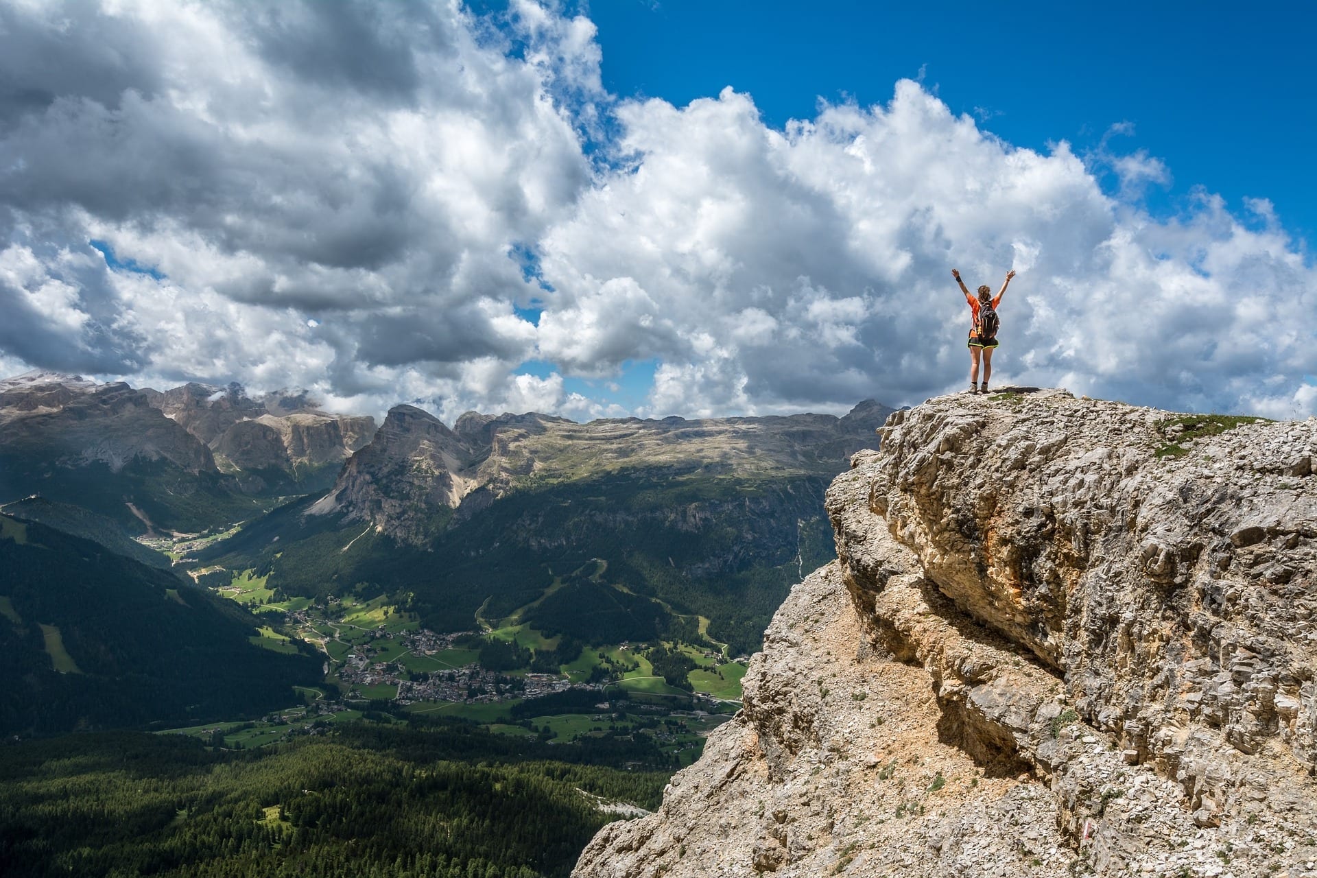 Someone standing at the top of a mountain, arms raised in triumph.