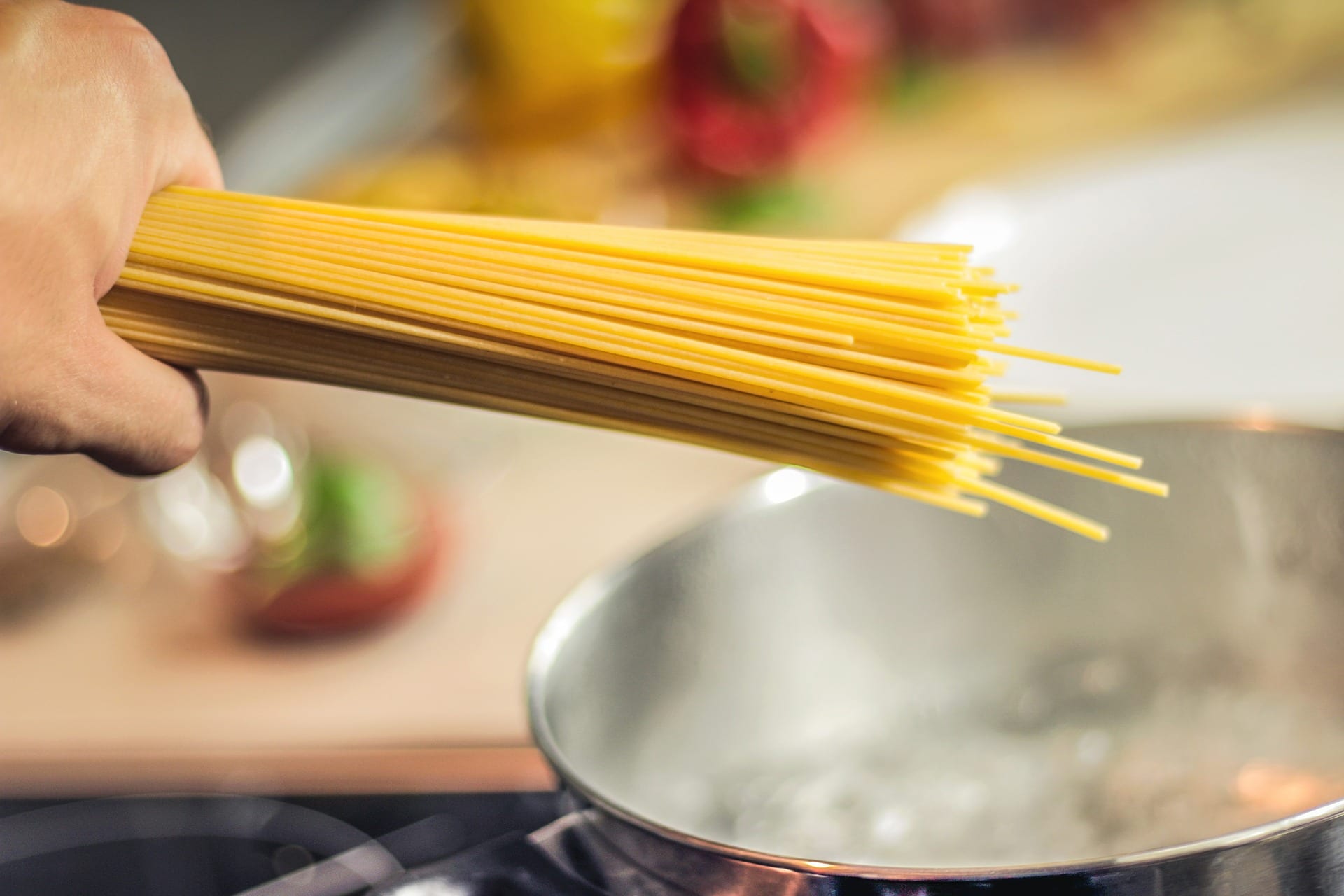 A handful of dried pasta being shown its watery fate by the hand of God.