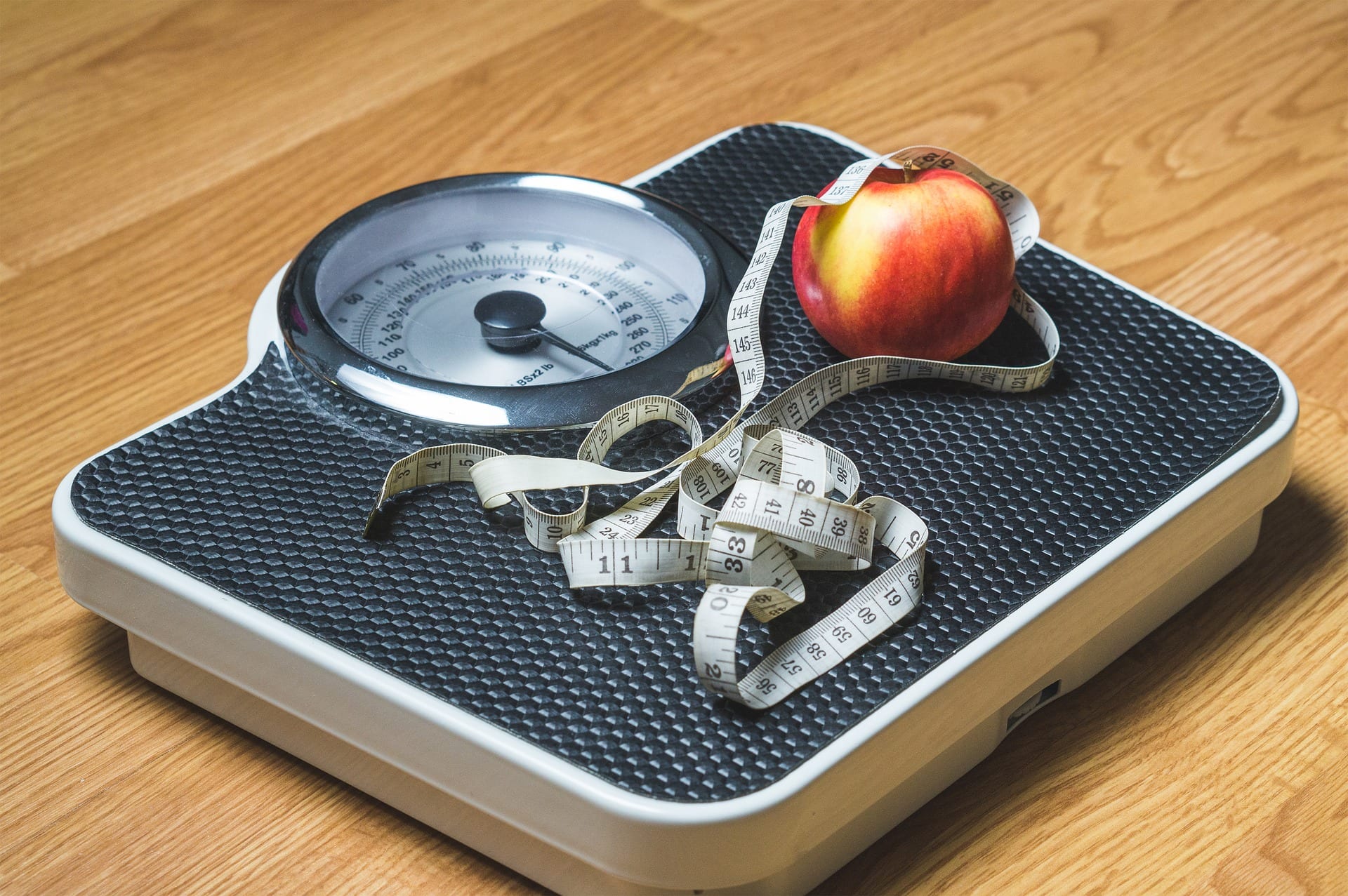 A household scale and measuring tape. There is also an apple on the scale for some reasons.