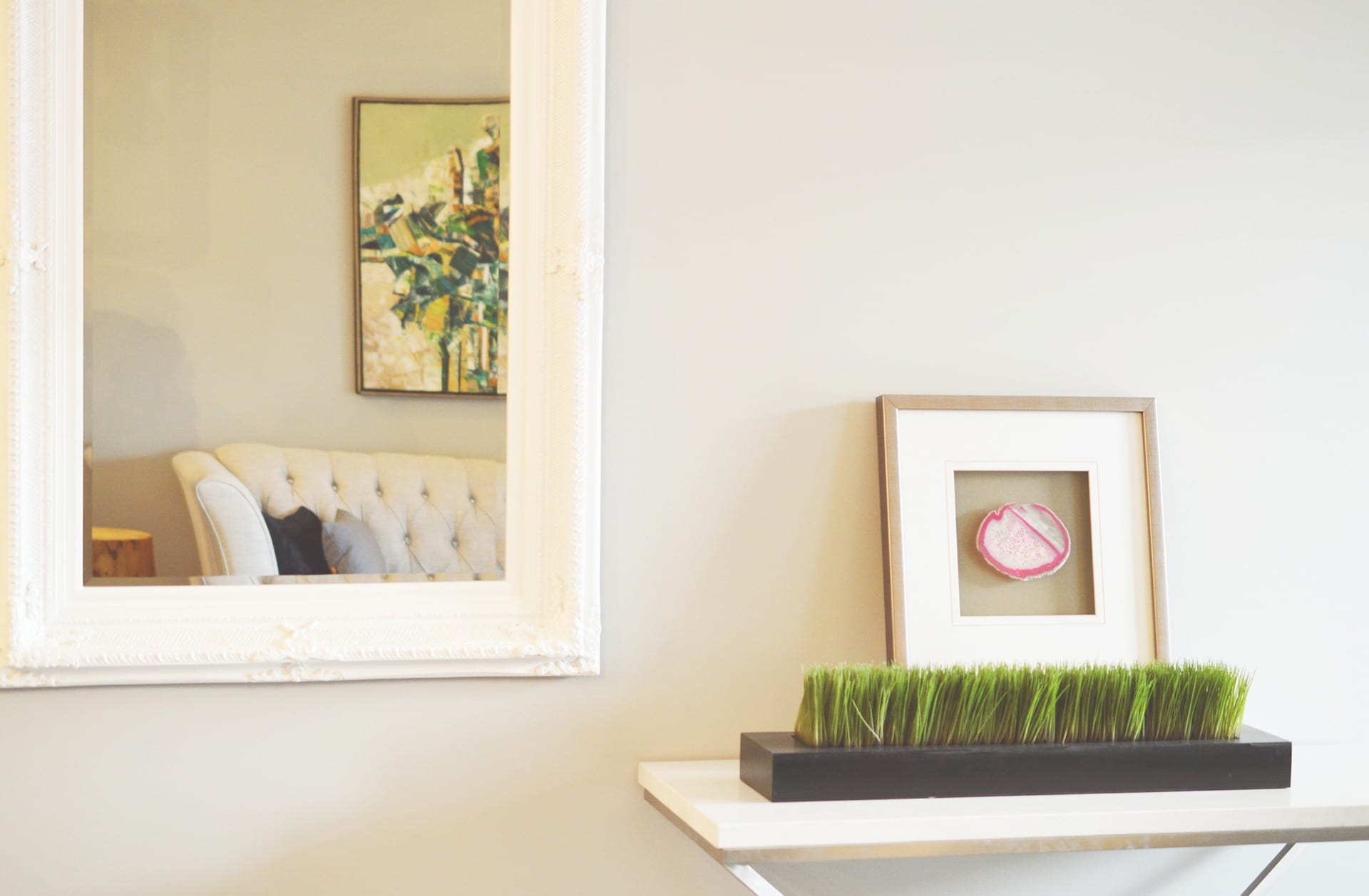 A tidied shelf against a wall with a mirror revealing a tidy couch.