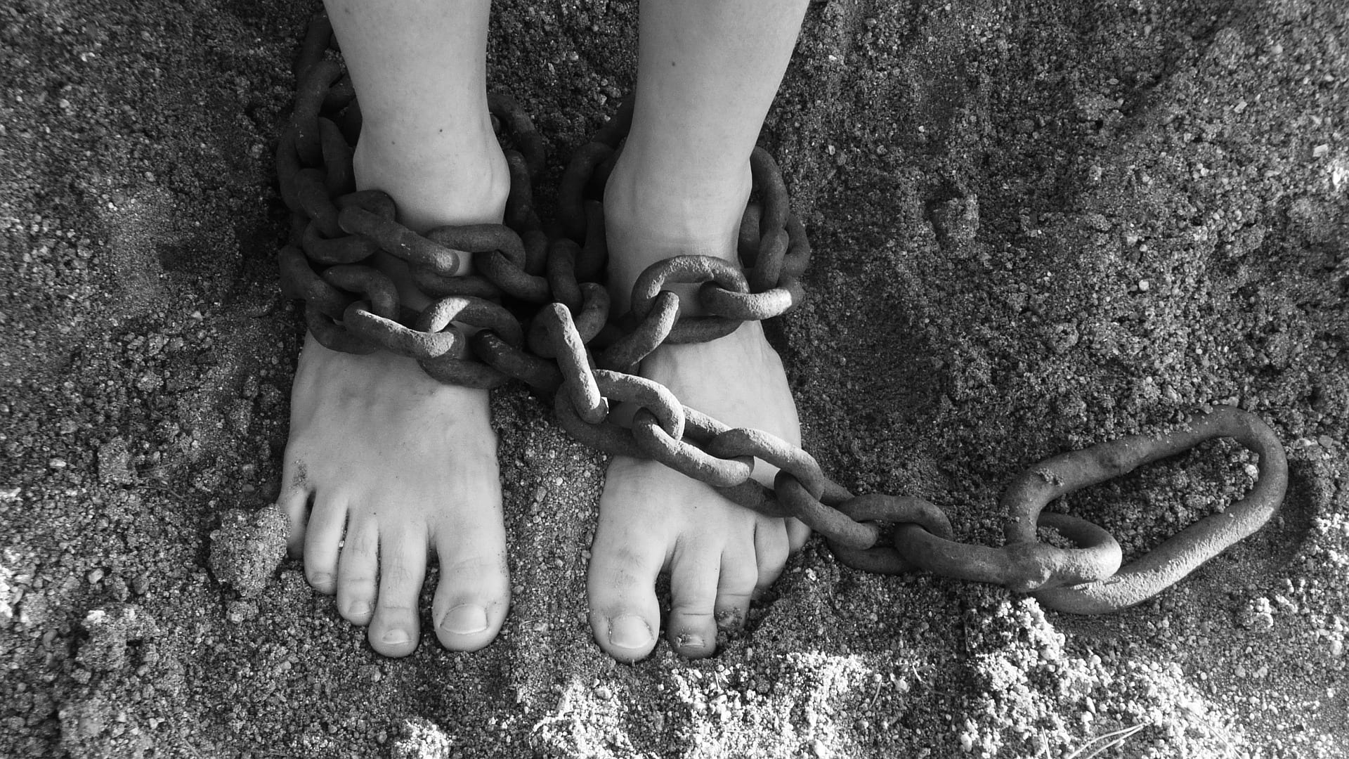 A black-and-white photo of feet, chained at the ankles.