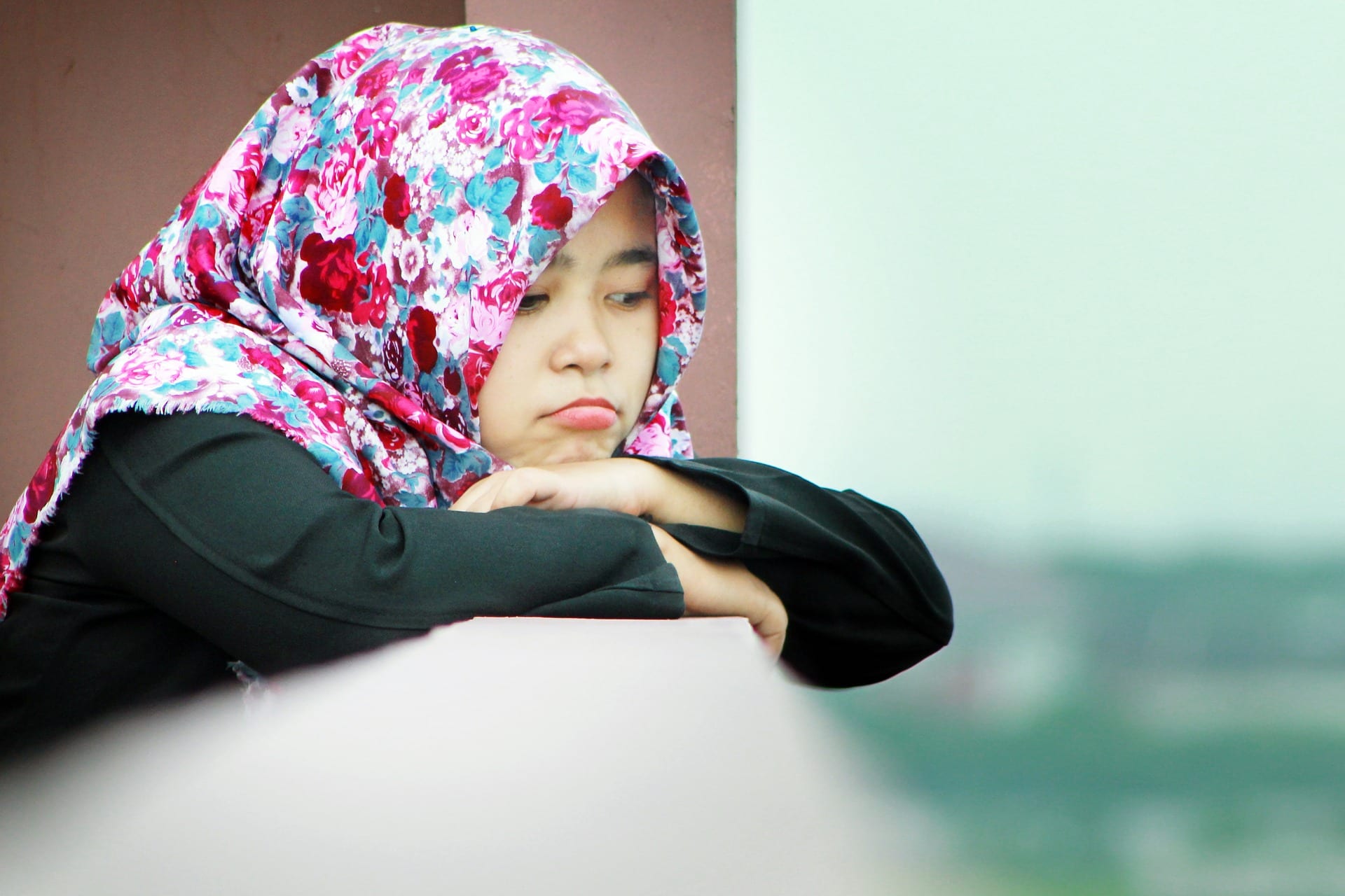 A young girl in a hijab looking forlorn.